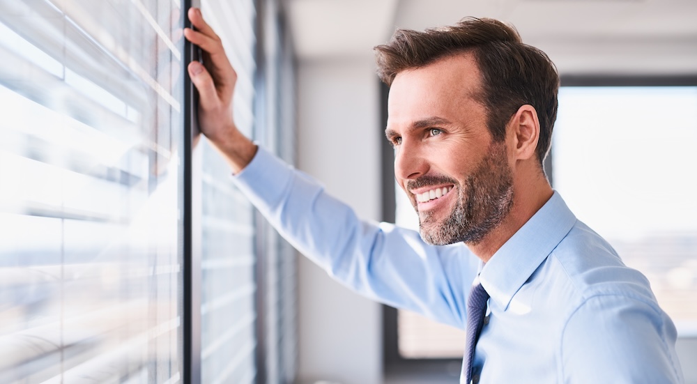 Happy businessman in office looking out the window