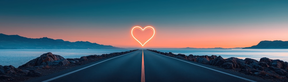 A serene road leads towards a glowing heart-shaped sign against a beautiful sunset backdrop, evoking feelings of love and adventure.