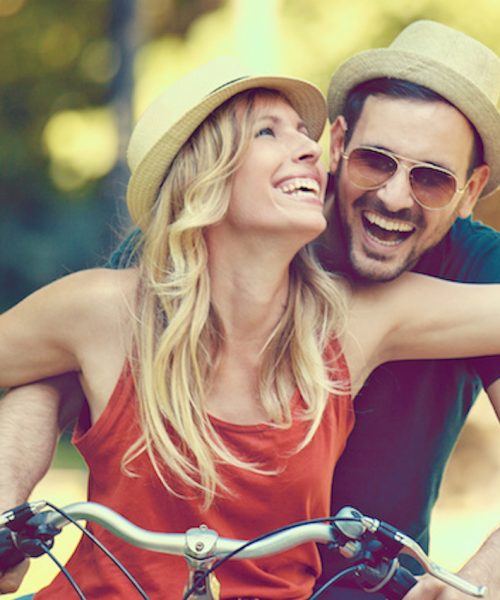 Portrait of happy young couple riding a bike in the park.