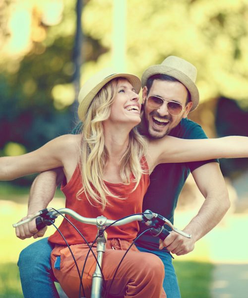 Portrait of happy young couple riding a bike in the park.