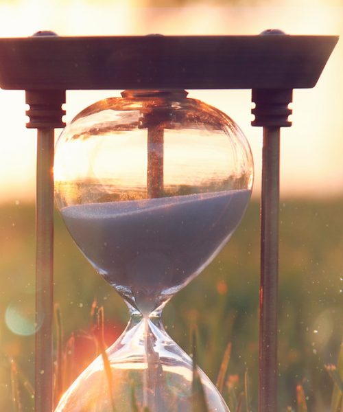 Hourglass in the grass time during sunset. vintage style