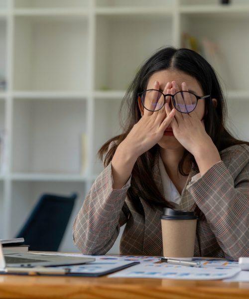 tired business woman sleepy and bored from sitting at a desk for a long time and has office syndrome