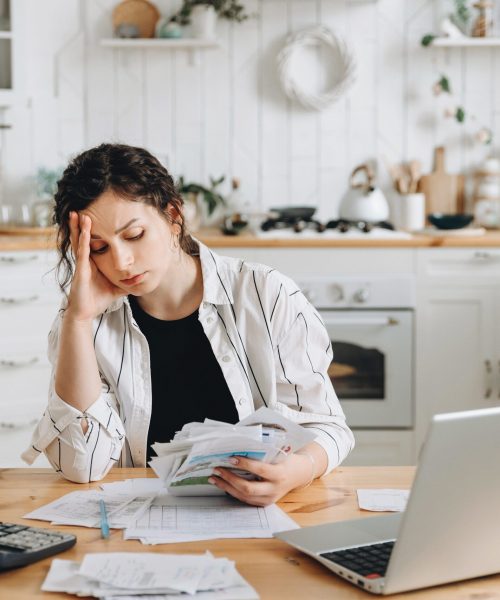 Stressed caucasian woman trying to deal with financial documents, having problem to find money to pay utility bills or loans. The concept of debt, bankrupt. Accounting companies advertisement mockup.