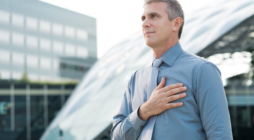 Portrait Of Mature Businessman Pledging With Hand On His Heart Outdoor