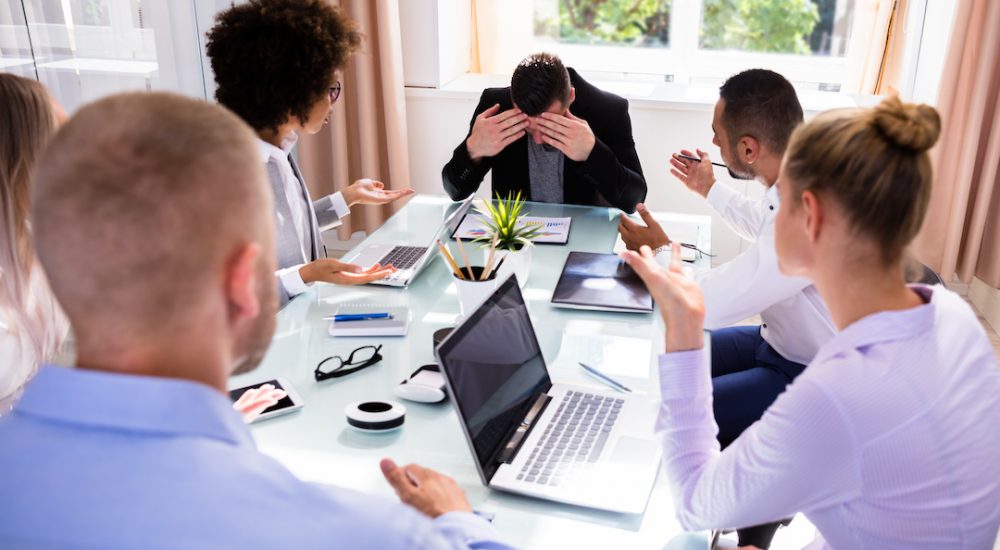 Businesspeople Blaming Their Depressed Young Male Colleague In Office