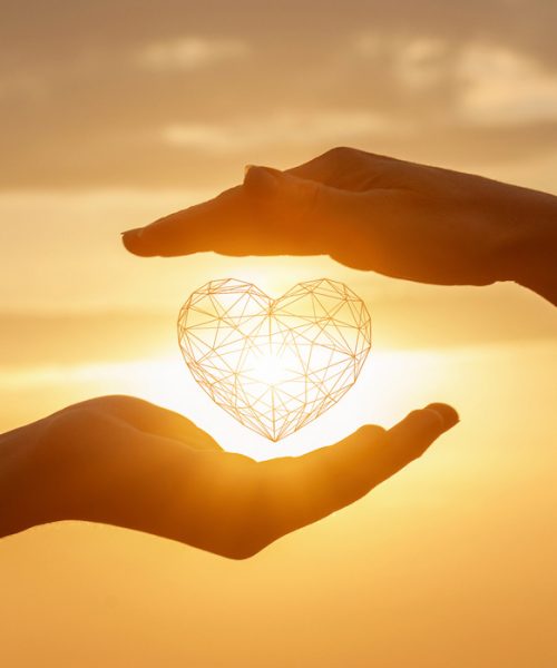 The concept of a love relationship between people. Hands interacts with a heart on a background of sunny sunset.